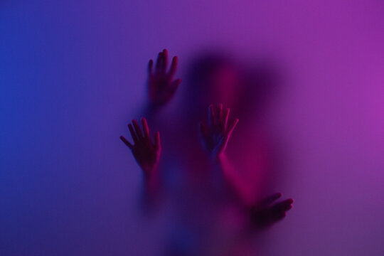 People make love behind the matte glass in purple light with passion