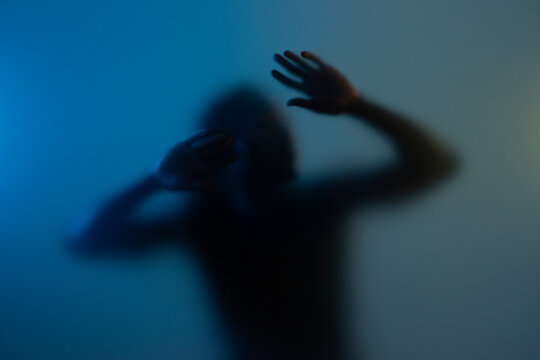 Black man touching frost glass at studio. Looking for help, emotional confinement concept. 
