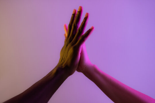 Peoples hands of different ethnicities touching each other against studio background