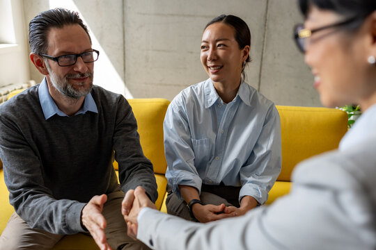 A diverse couple shaking hands with a real estate professional after a successful property consultation. Business lifestyle concept of trust, investment, and homeownership.