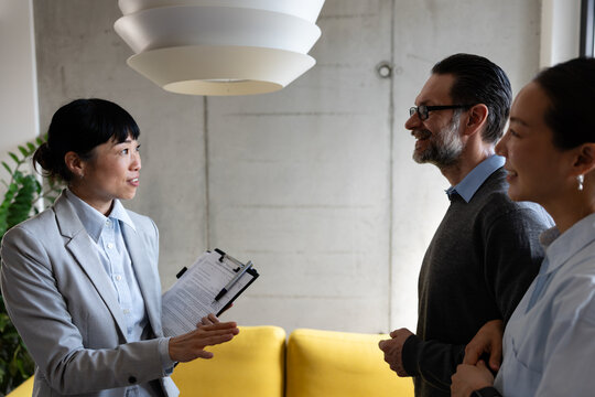 Real estate agent meeting with a multicultural couple during a property consultation. Professional discussion about buying, renting, or investing in a new home.