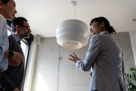 Professional real estate advisor explaining housing options to a mature multicultural couple. Concept of renting, investing, relocation, and property planning