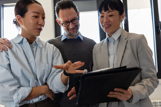 Happy diverse couple on an apartment tour with their real estate agent. Smiling multicultural buyers talking to a realtor, exploring a new property, home, or commercial space to rent or buy.