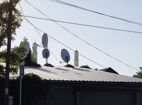 old parabolic antennas on the roof against the background of minarets