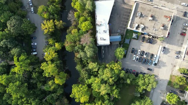Aerial view over Bloor Street West in the Kingsway neighborhood of Toronto, Ontario, Canada. Flying forward, looking down onto Mimico Creek, houses, buildings, passing traffic and a soccer field.