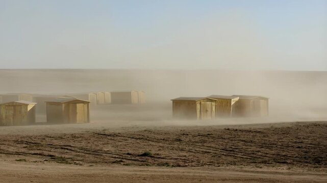 Desert windstorm sweeps across isolated outpost with wooden structures battling dust
