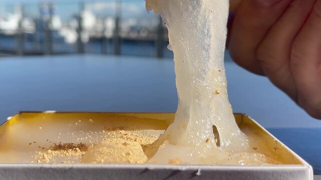 きな粉をトッピングした和菓子のわらび餅。食べたいけど切れず、力強く伸びているわらび餅の動画。