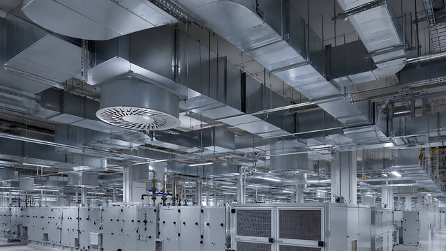 Clean industrial ventilation system with ceiling ducts and air handling equipment inside modern factory facility