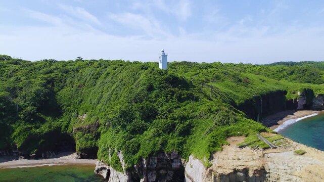 石川県 加佐の岬の白い灯台と断崖に迫るドローン空撮 前進・上昇 / Aerial drone pushing in and ascending towards the white lighthouse and cliffs at Cape Kasa, Ishikawa