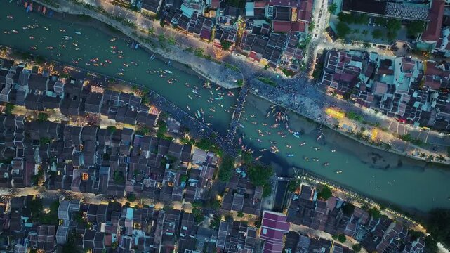 Vertical aerial perspective of Hoi An neighborhoods divided by the Thu Bon River at dusk.