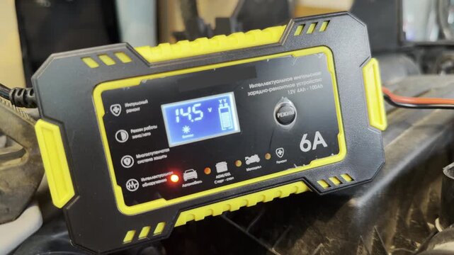 A digital battery charger powers a vehicle battery inside the engine bay. This active power transfer generates a steady electrical hum.