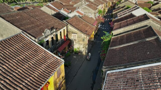 Bougainvillea decorates a narrow street surrounded by traditional architecture in Hoi An.