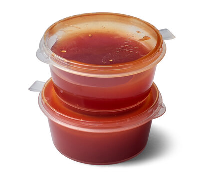 stacked small clear plastic red tomato sauce containers isolated white background, disposable transparent portion cup packaging serve along with pizzas, takeaway food condiment