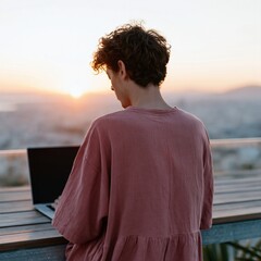 Fototapeta premium Young person working on laptop on rooftop balcony at sunset for remote work background and banner