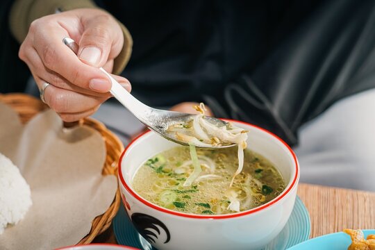 Eating traditional Indonesian soto soup with a spoon close up