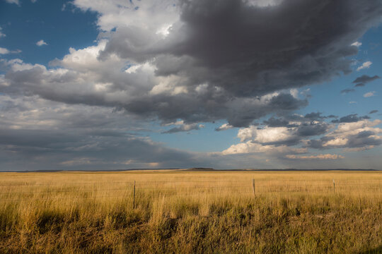 Storm clouds over open rangeland and rural property line