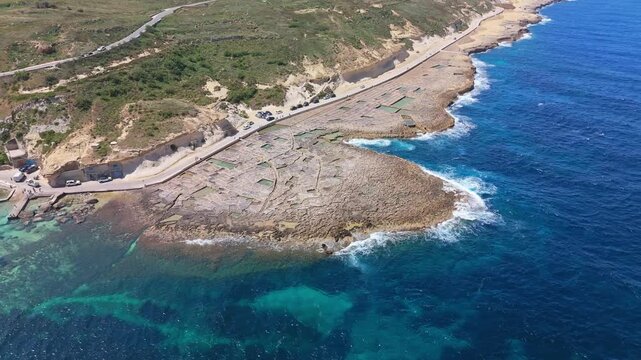 From above, Xwejni&rsquo;s ancient salt pans carve a mosaic into Gozo&rsquo;s rocky coast, where turquoise Mediterranean waters swirl against the Maltese shoreline.