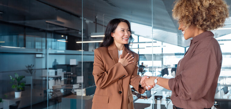 Business woman entrepreneur hiring employee after successful interview. Two businesswomen shaking hands in office, smiling during professional meeting, teamwork and partnership. Banner, copy space