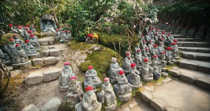 Stone Jizo Statues with Red Hats Along Temple Garden Path in Japan - steady cam