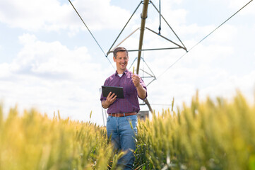 Farmer using tablet in wheat field with irrigation system © Dexon Dee