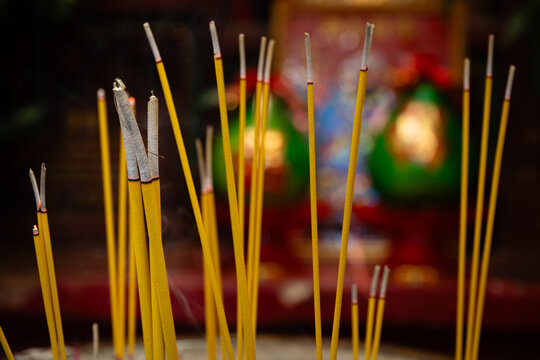 Yellow incense sticks burning in a censer at the Hung Shing Temple on Queen's Road East in Wan Chai, with a blurred deity statuette visible in the background