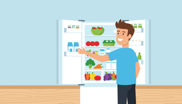 Smiling young man looking inside a double door refrigerator filled with fresh vegetables milk and healthy food.