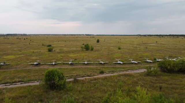 Abandoned airfield with trainer jet aircrafts Aero L-29 parked in line reclaimed by vegetation