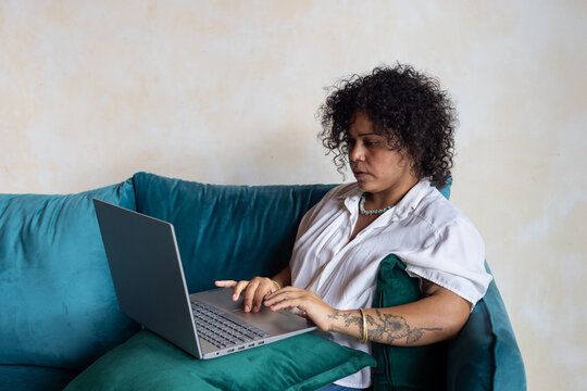 focused woman working on laptop computer from couch