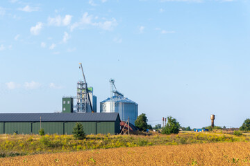 Fototapeta premium Farm Buildings and Silos Stand Under a Clear Sky With a Field in the Foreground During a Sunny Afternoon in Rural America
