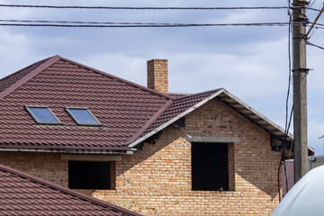 Obraz premium Construction of Brick House With Roof Windows Under Cloudy Sky in Residential Area