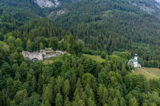 Aerial view of the medieval Burgruine Thaur castle ruin and Romedikirchl chapel on forested ridges in Thaur, Tyrol, Austria