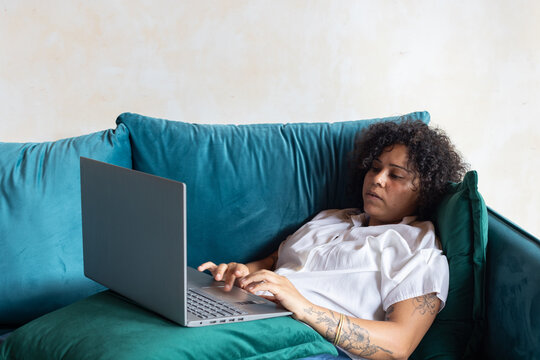 tired focused woman working on laptop computer from couch