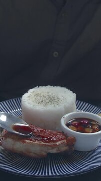 Close-up focus on glazing soysauce and vinegar condiment over pritong manok or fried chicken, capturing a dining moment enjoying authentic Filipino food. Dauin, Philippines