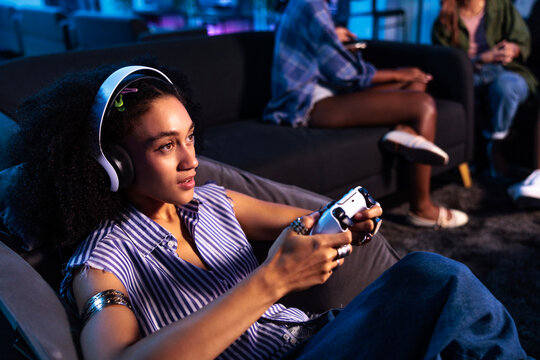 Woman gaming with friends in a dimly lit room.