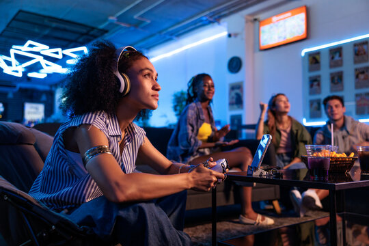 Friends gaming together in a neon-lit room.