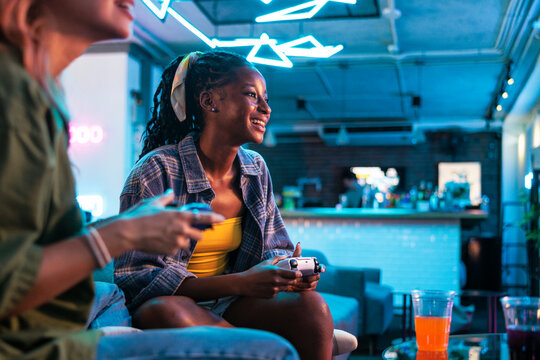 Friends gaming in a neon-lit bar, smiling.
