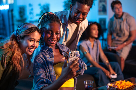 Friends gather, smiling, taking a selfie at a casual party.