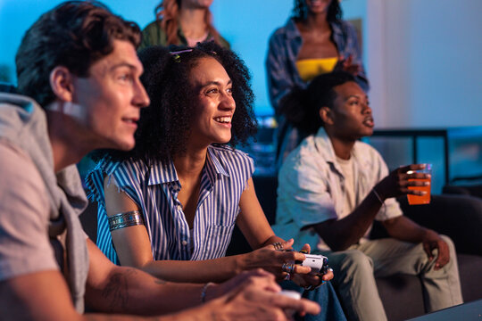Friends enjoy gaming together, laughing and focused on the screen.