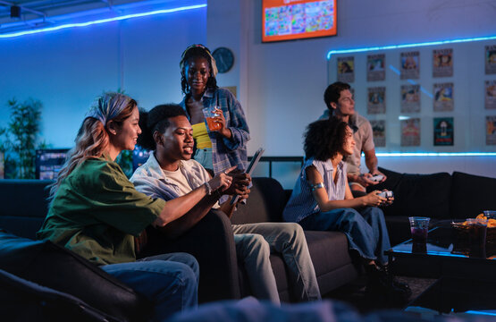 Friends gather in a gaming lounge, playing and watching.