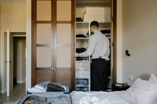Man Organising Clothes in Closet in Bedroom