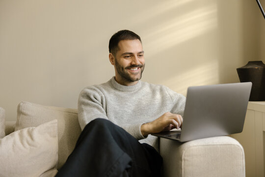 Man Working on Laptop at Home While Seated on Couch