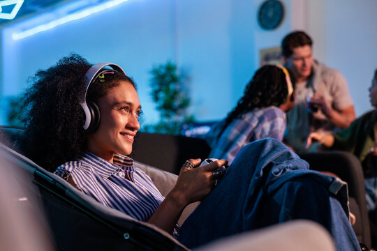 Woman gaming with friends in a blue-lit room.
