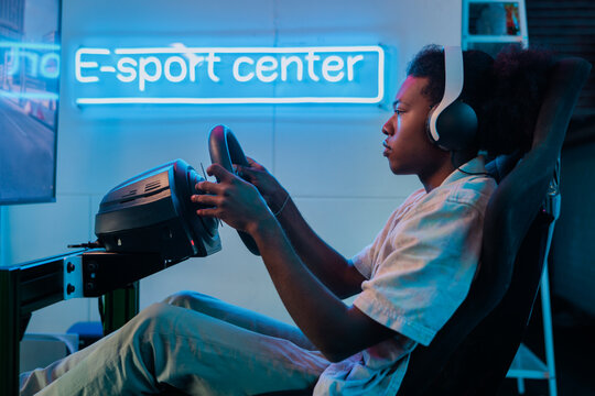 Esports gamer using racing simulator with neon sign.