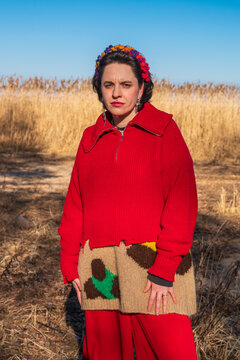 Woman in red sweater standing in dry field portrait
