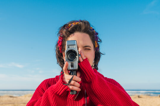 Person filming with handheld camcorder on sunny beach