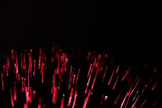 Fiery red fiber optic threads glow like digital embers against deep black background.