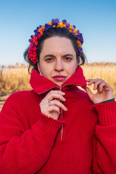 Woman in red sweater adjusting collar with colorful headband