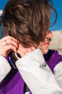 Close-up of woman adjusting pearl earring in sunlight