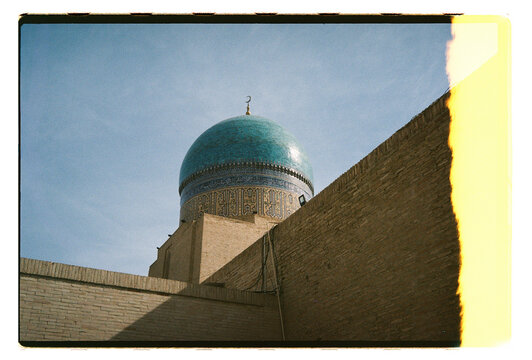 Turquoise dome of a mosque against clay walls in Uzbekistan