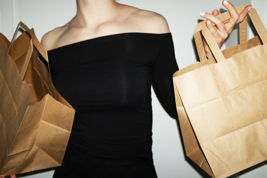 Person holding brown mockup paper bag with empty space for text